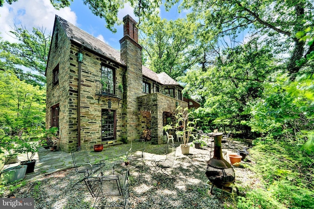 218 Parkside Ave, Trenton, NJ 08618 - back of house with a high end roof, stone siding, a chimney, and a patio area