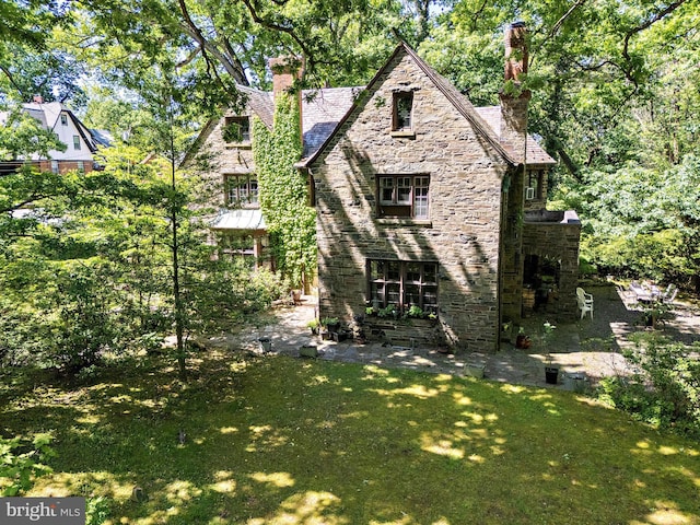 218 Parkside Ave, Trenton, NJ 08618 - rear view of house with a chimney, stone siding, a lawn, and a high end roof