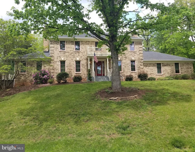 view of front of home with a front yard, brick siding, and a balcony