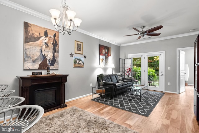 living area with baseboards, ornamental molding, wood finished floors, and ceiling fan with notable chandelier