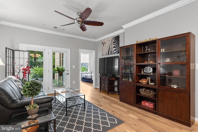 living room with visible vents, crown molding, baseboards, ceiling fan, and light wood-type flooring