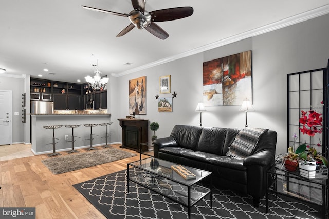 living room with baseboards, ceiling fan with notable chandelier, light wood finished floors, ornamental molding, and recessed lighting