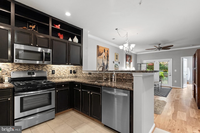 kitchen with decorative backsplash, a sink, a peninsula, ornamental molding, and stainless steel appliances