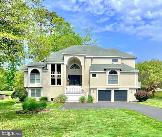 view of front of property featuring asphalt driveway, stucco siding, a front lawn, and an attached garage