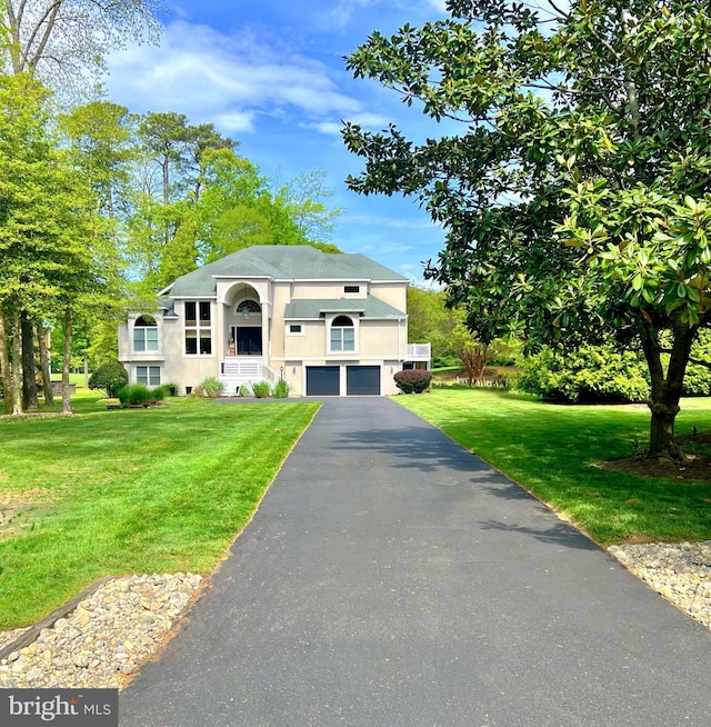 view of front of house with a garage, stucco siding, asphalt driveway, and a front yard