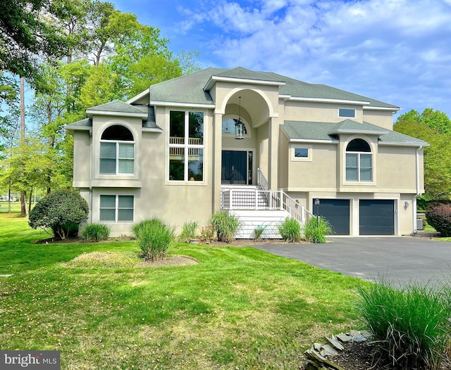 view of front of property featuring stucco siding, asphalt driveway, a garage, and a front yard