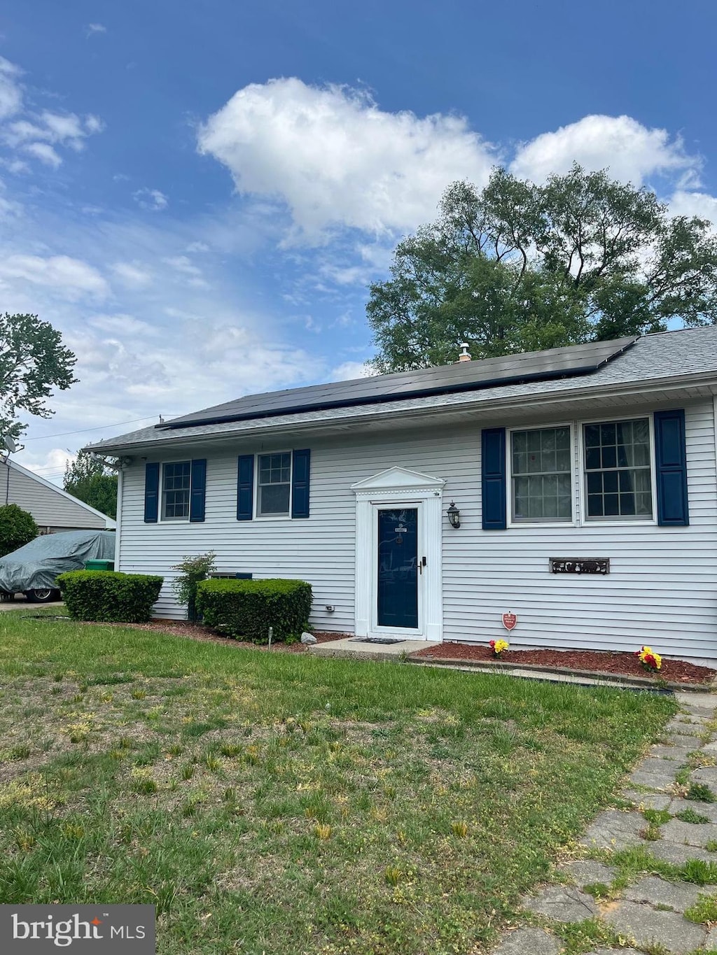 bi-level home with roof mounted solar panels and a front yard