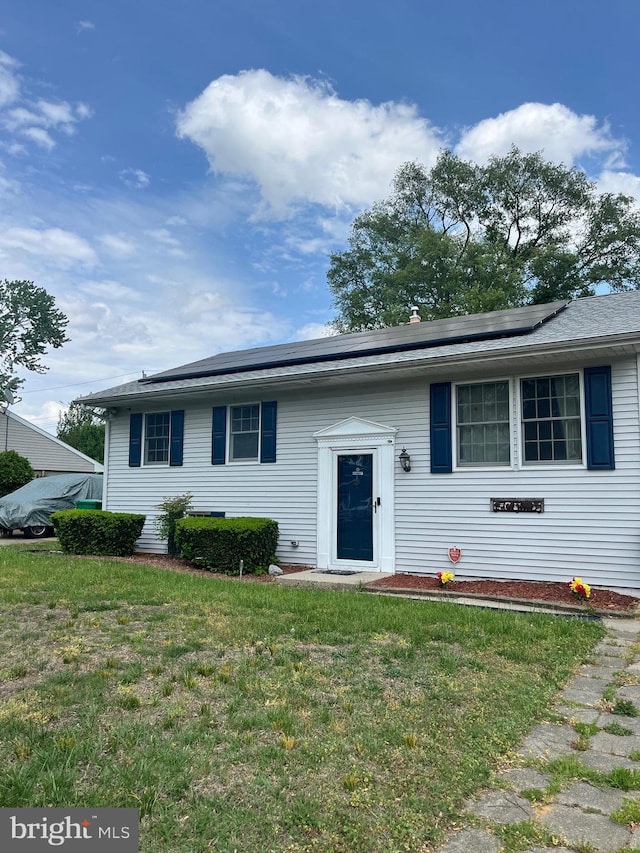 bi-level home with roof mounted solar panels and a front yard