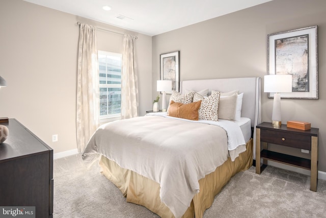 bedroom featuring baseboards, light colored carpet, and visible vents