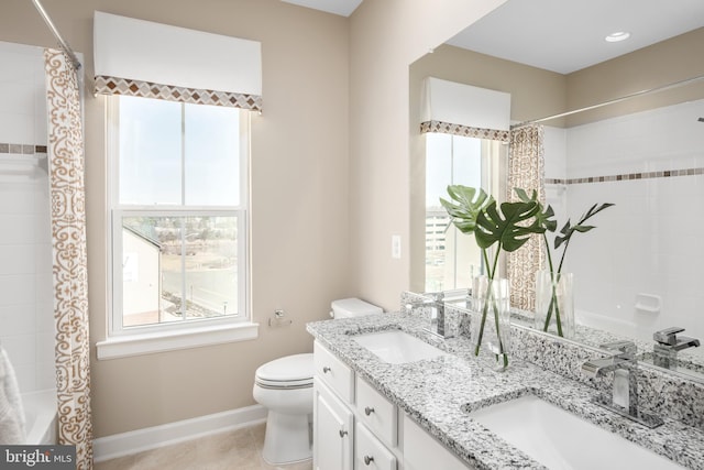 full bath with a sink, baseboards, toilet, and double vanity