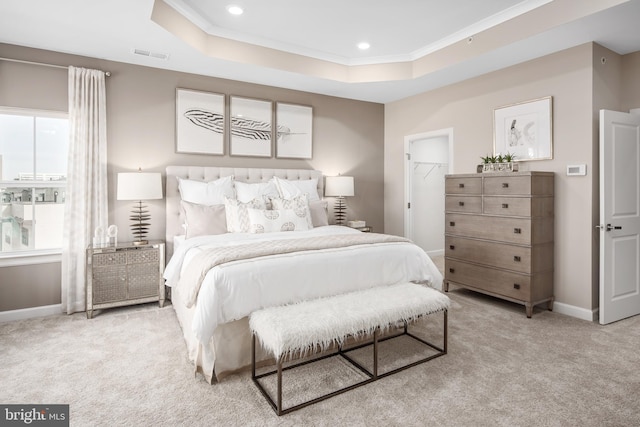 carpeted bedroom with crown molding, visible vents, baseboards, a walk in closet, and a raised ceiling