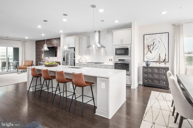 kitchen featuring a kitchen breakfast bar, a large island, stainless steel appliances, wall chimney exhaust hood, and dark wood-type flooring