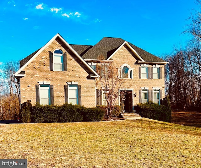 view of front facade featuring brick siding and a front yard