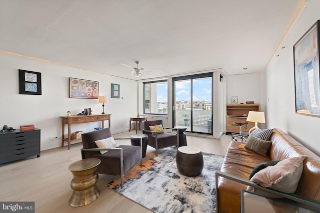 living room featuring light wood-style flooring, ceiling fan, a desk, and baseboards