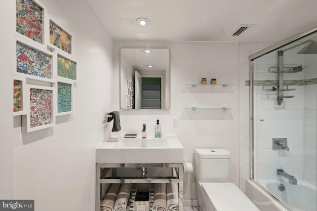 bathroom with toilet, combined bath / shower with glass door, a sink, and recessed lighting
