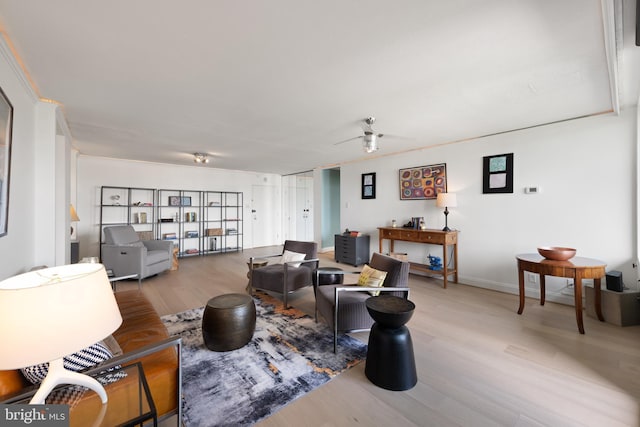 living room featuring light wood finished floors, ceiling fan, and baseboards