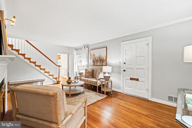 708 W Timber Branch Pkwy, Alexandria, VA 22302 - living room with light wood finished floors, a fireplace, stairway, baseboards, and crown molding