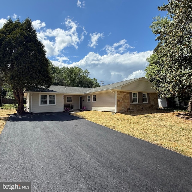 ranch-style house featuring aphalt driveway and stone siding