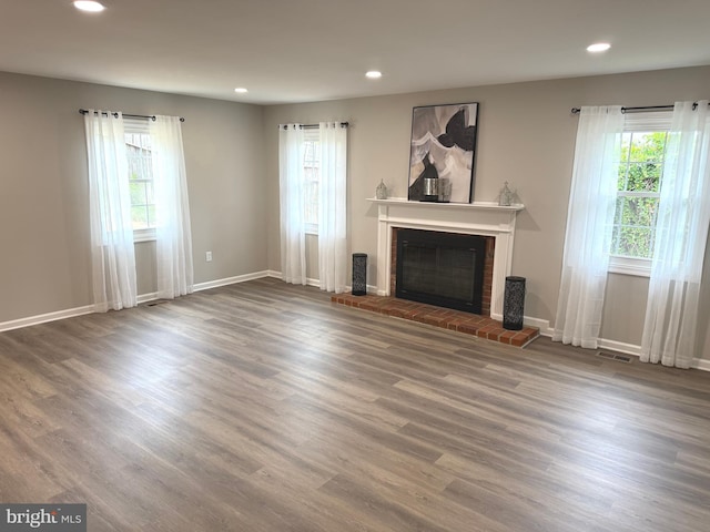 unfurnished living room featuring wood finished floors, a fireplace, visible vents, baseboards, and recessed lighting