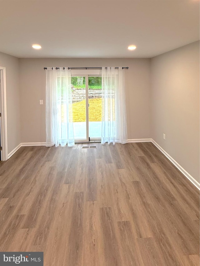 empty room with recessed lighting, baseboards, and wood finished floors
