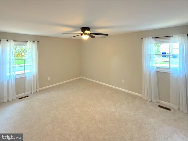 empty room featuring baseboards, ceiling fan, light carpet, and visible vents