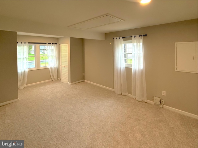 empty room with carpet flooring, attic access, and baseboards