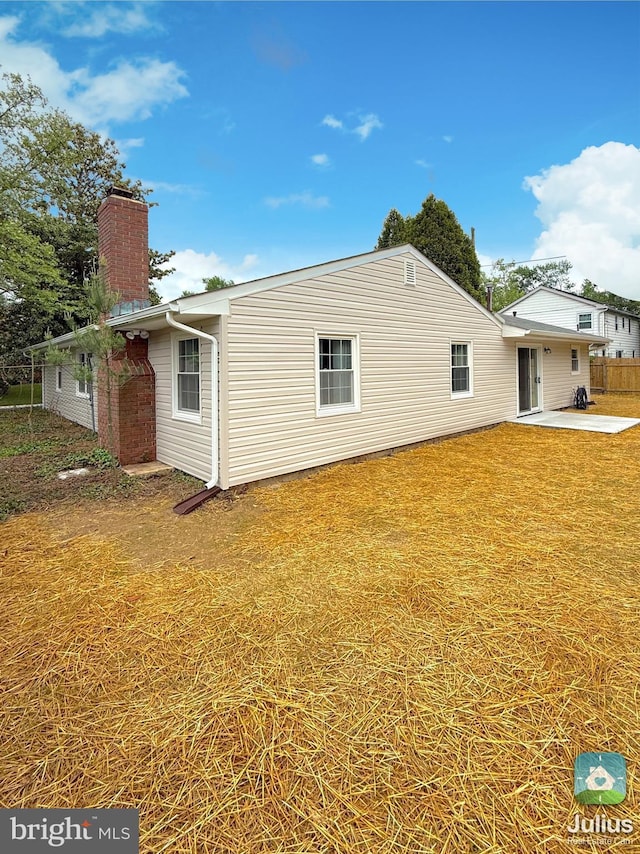 rear view of house featuring a yard, a patio area, and a chimney