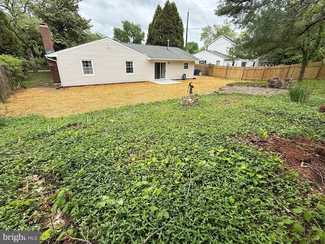 rear view of property featuring a yard, a chimney, a patio area, and a fenced backyard