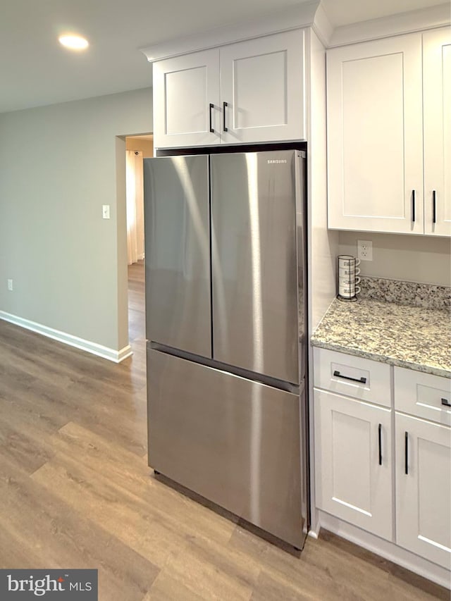 kitchen with freestanding refrigerator, baseboards, white cabinetry, and light wood-type flooring