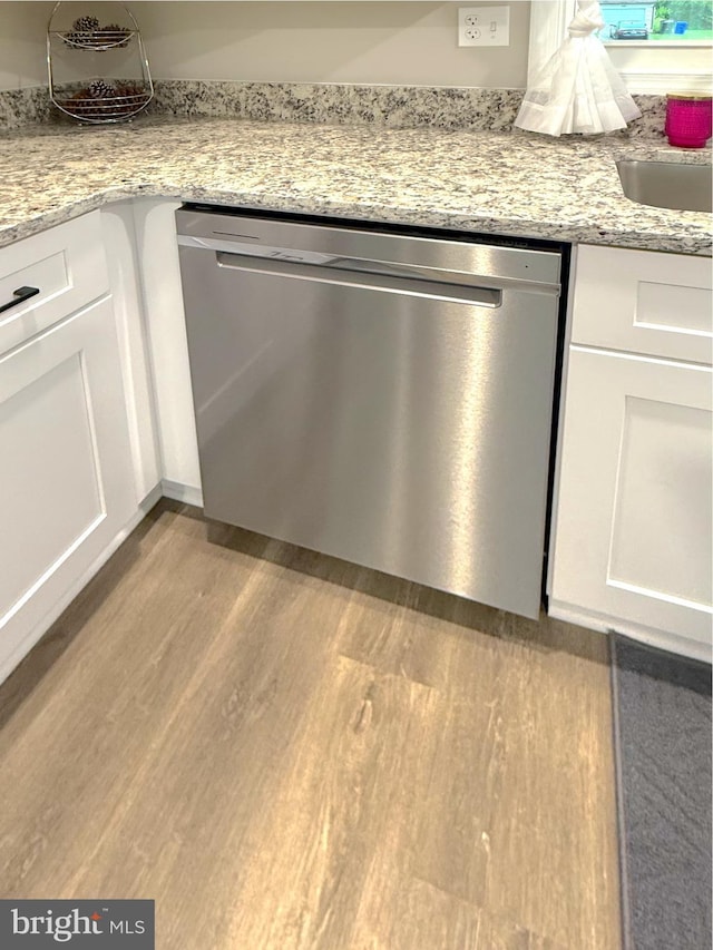 room details featuring dishwasher, light stone counters, a sink, white cabinetry, and wood finished floors