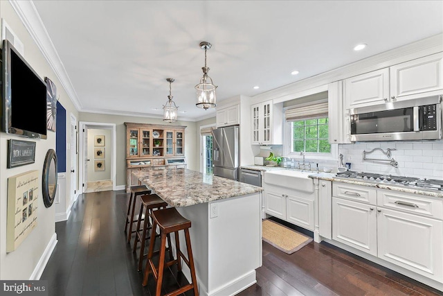 kitchen featuring a kitchen island, glass insert cabinets, a sink, dark wood finished floors, and appliances with stainless steel finishes