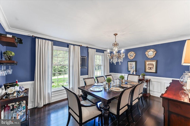 dining area featuring crown molding, dark wood-style flooring, a chandelier, and a wainscoted wall