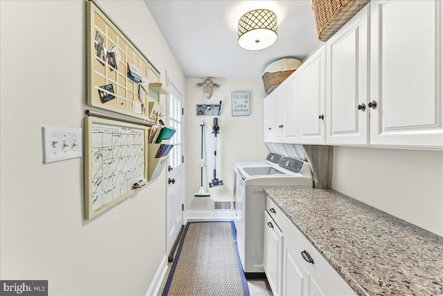 clothes washing area with baseboards, visible vents, cabinet space, and washer and clothes dryer