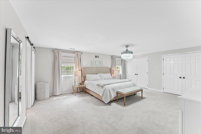 bedroom featuring visible vents, multiple closets, baseboards, light colored carpet, and a chandelier