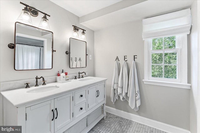 full bath featuring a sink, baseboards, tile patterned floors, and double vanity