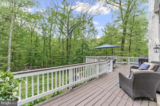 deck featuring a playground, a yard, and grilling area