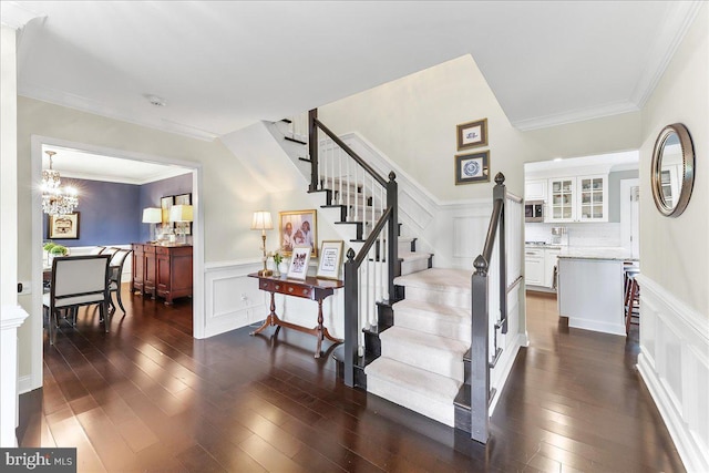 stairway featuring wood-type flooring, an inviting chandelier, wainscoting, and a decorative wall