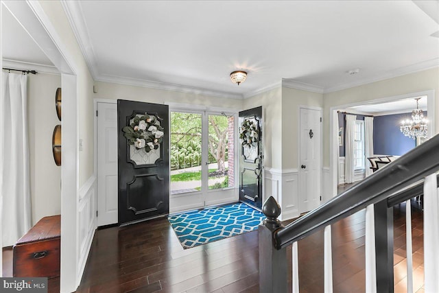 entryway with an inviting chandelier, crown molding, a decorative wall, and wood finished floors