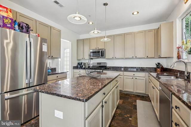 kitchen with appliances with stainless steel finishes, a sink, dark stone finish flooring, recessed lighting, and a center island