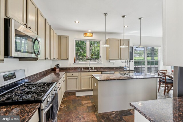 kitchen with appliances with stainless steel finishes, a sink, dark stone finish floors, healthy amount of natural light, and recessed lighting