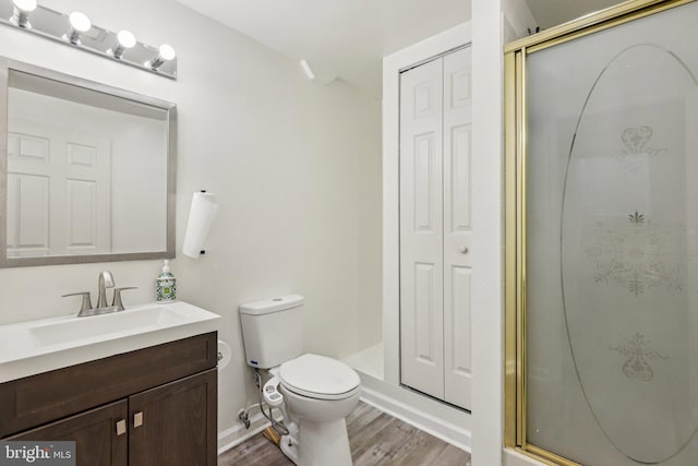 bathroom with toilet, wood finished floors, a stall shower, and a closet