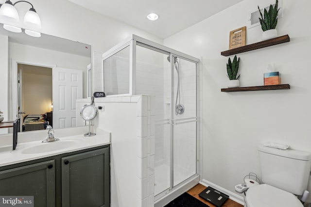 ensuite bathroom featuring toilet, a stall shower, vanity, and wood finished floors