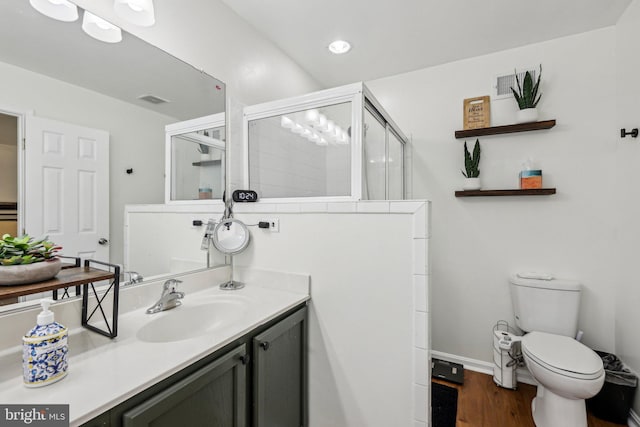 full bath with a tile shower, toilet, wood finished floors, vanity, and baseboards