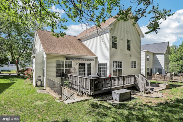 rear view of property featuring a wooden deck, roof with shingles, and a yard