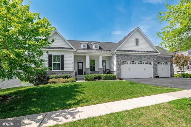 craftsman inspired home with an attached garage, aphalt driveway, a front lawn, a porch, and a standing seam roof
