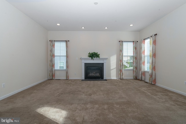 unfurnished living room featuring a fireplace with flush hearth, carpet floors, baseboards, and recessed lighting