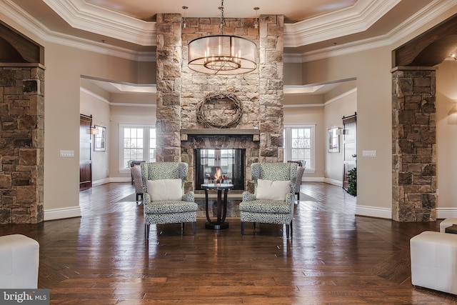 sitting room featuring ornamental molding, a stone fireplace, hardwood / wood-style flooring, and baseboards