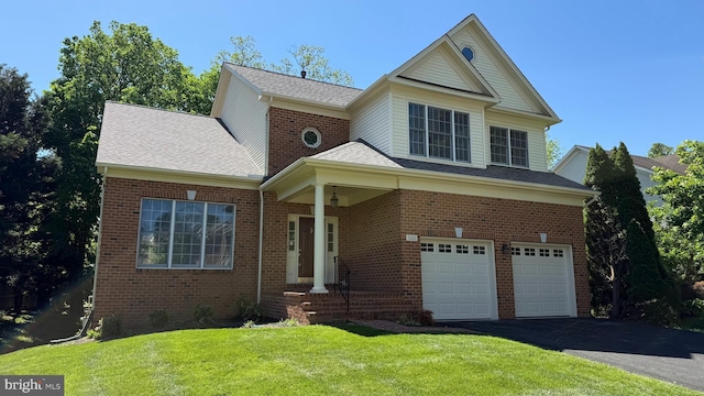 traditional-style house with an attached garage, driveway, a front lawn, brick siding, and roof with shingles