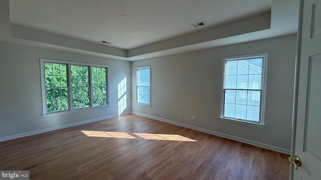 empty room with baseboards, dark wood finished floors, and a raised ceiling