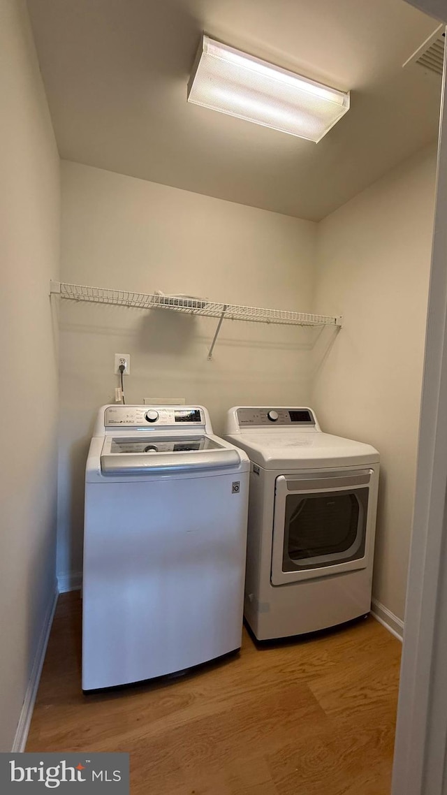 laundry area featuring washer and dryer, light wood finished floors, and baseboards